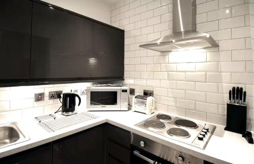 a kitchen with a stove and a microwave at 3 Person Apartment with Priv Entrance and Carpark in Stockport