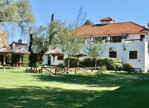 een huis met een tuin met picknicktafels en bomen bij Hosteria los Cesares in Merlo