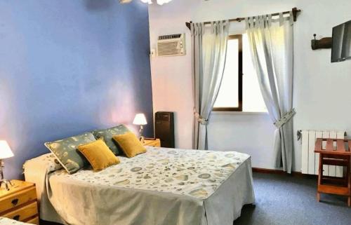 een blauwe slaapkamer met een bed met gele kussens bij Hosteria los Cesares in Merlo