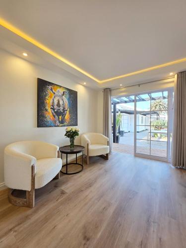 White Cottage Boutique Guesthouse في سواكوبموند: غرفة معيشة مع أريكة وكراسي وطاولة