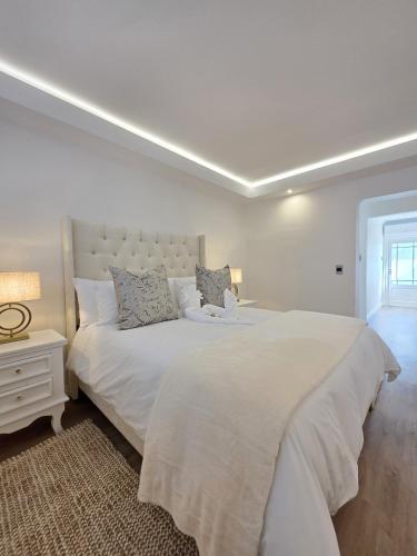 White Cottage Boutique Guesthouse في سواكوبموند: غرفة نوم بيضاء مع سرير كبير ونافذة