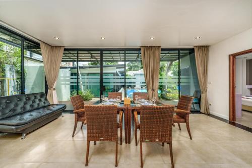 a dining room with a table and chairs and a couch at Villa Navin Beach Residence in Jomtien Beach