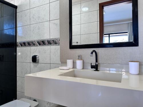 Un baño blanco con lavabo y espejo. en B484 - Apto 3 quartos perto do mar e com vista., en Bombas