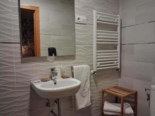 a white bathroom with a sink and a mirror at Hostal La Pastora in Candeleda