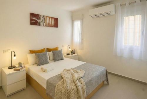a white bedroom with a bed and a window at Apartamentos Benalua Alicante - Con Parking - Elegir en el momento de la reserva in Alicante