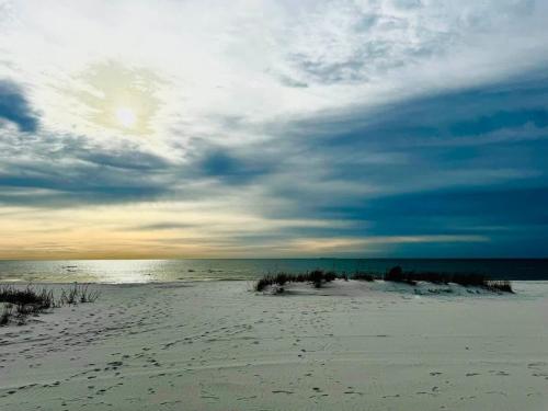 a sandy beach with a cloudy sky and the ocean at NEW Getaway by Gulfport Beach in Gulfport