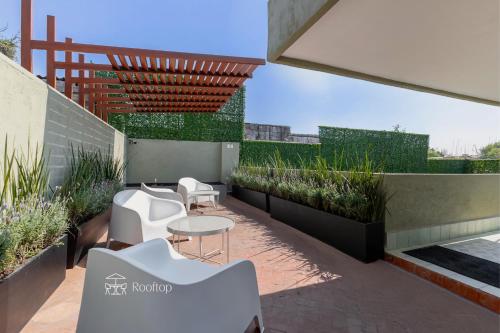 a patio with white chairs and tables and plants at Kin Pech Roma by Capitalia in Mexico City