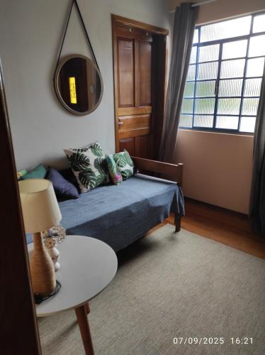 een woonkamer met een bed en een tafel bij Sítio Cachoeira de Minas in Cachoeira de Minas