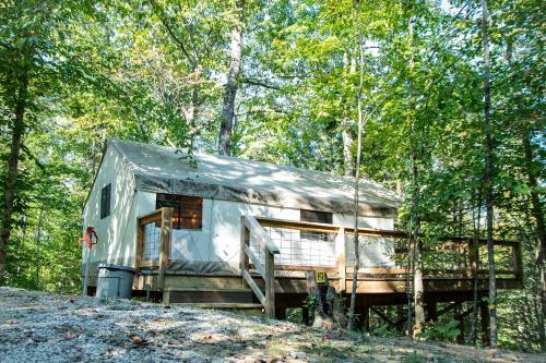 an old silver trailer parked in the woods at Blue Heron's Nest - Glamping Tent in the Gorge with AC in Rogers