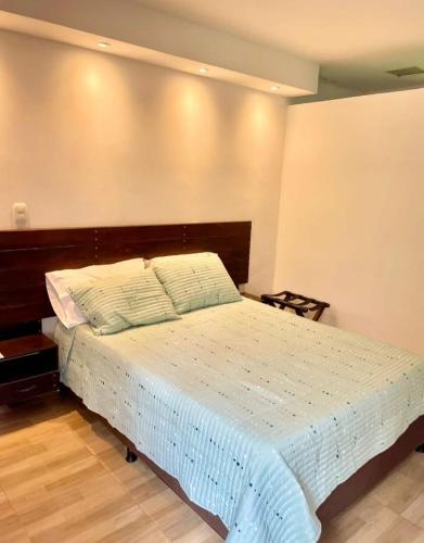 een slaapkamer met een bed met een houten hoofdeinde bij Hotel EL QUIMBO in Garzón