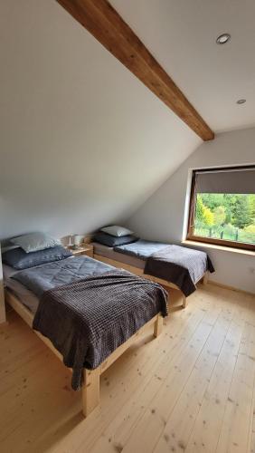 two beds in a bedroom with a large window at Piernikowa Chata in Zawoja