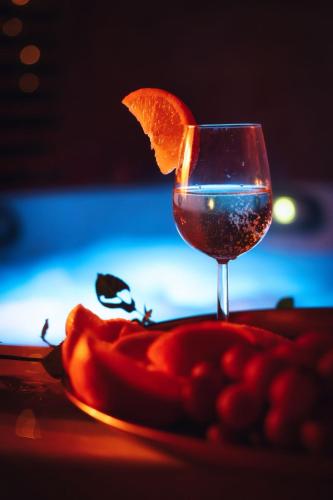 a glass of wine with an orange on a plate at Domki KOLONIA LEŚNA z sauną i gorącą balią in Radków