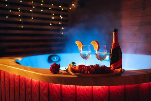 uma mesa com um prato de frutas e uma garrafa de vinho em Domki KOLONIA LEŚNA z sauną i gorącą balią em Radków