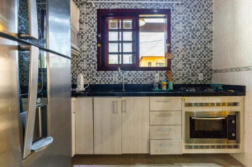 een keuken met een wastafel, een fornuis en een raam bij Aconchego in Mangaratiba