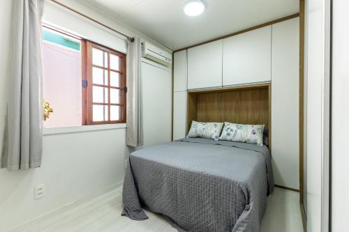 een kleine slaapkamer met een bed en een raam bij Aconchego in Mangaratiba