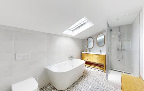 a white bathroom with a tub and a sink at Maison Charentaise 12 à 14 personnes in Sémussac