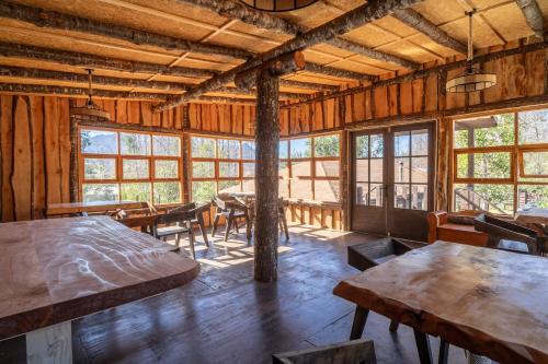 a large room with tables and chairs and windows at Pucón REC-Lodge Cabañas Las Bandurrias in Pucón