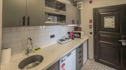 a kitchen counter with a sink and a black door at Balat Side Apart in Istanbul