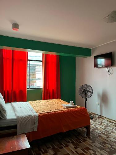 a bedroom with a bed with red curtains and a fan at Hotel PRADO'S in Satipo