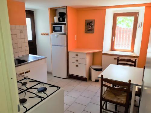 a kitchen with orange walls and a stove top oven at Gite Le Vignou À Ste-enimie in Prades