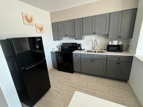 a kitchen with gray cabinets and a black refrigerator at Englewood Inn & Suites in Englewood