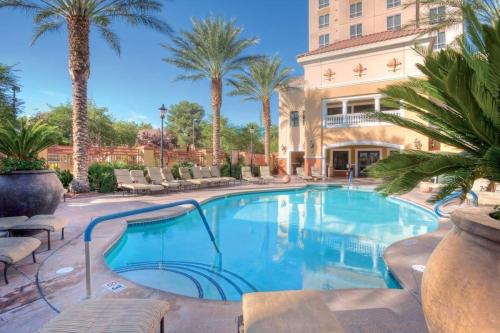 a swimming pool with palm trees and a building at Wyndham Grand Desert -3BR - Apartment With Resort Access in Las Vegas
