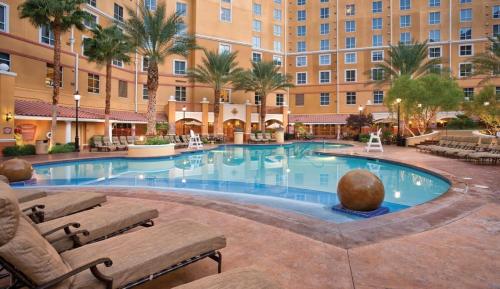 a pool at a hotel with chairs and a building at Wyndham Grand Desert -3BR - Apartment With Resort Access in Las Vegas
