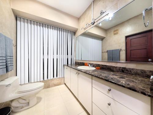 a bathroom with a toilet and a sink and a mirror at YC 1701 Apartamento 2 BDR av Balboa in Panama City