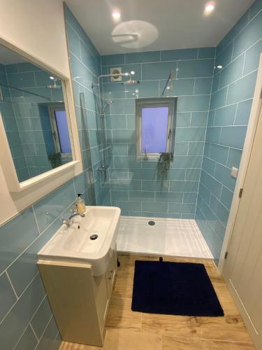 a blue tiled bathroom with a sink and a shower at Salcombe Bolthole Room in Salcombe