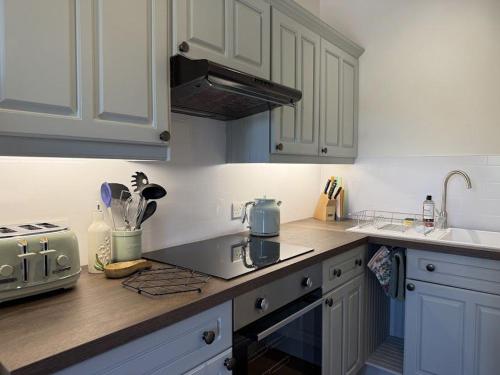 een keuken met witte kasten en een aanrechtblad bij The Cottage in Borrowdale Valley