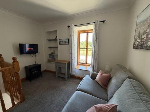 een woonkamer met een bank en een raam bij The Cottage in Borrowdale Valley