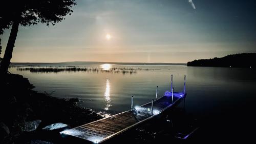 Waterfront 2-BR Cottage Retreat in Manitoulin Island في Kagawong: قارب على بحيرة والشمس في الماء