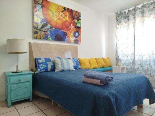 a bedroom with a blue bed and a painting on the wall at Habitación privada en casa de huespedes in Guadalajara