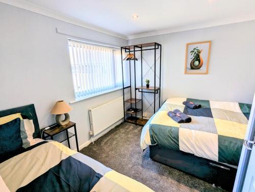 a bedroom with two beds and a window at Castleford nest 3 bed driveway 2 Free Parking 6ppl in Featherstone