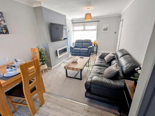 a living room with a leather couch and a table at Castleford nest 3 bed driveway 2 Free Parking 6ppl in Featherstone
