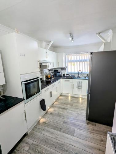 a kitchen with white cabinets and a wooden floor at Castleford nest 3 bed driveway 2 Free Parking 6ppl in Featherstone