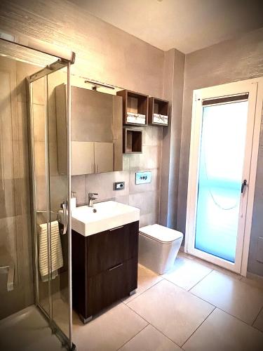 a bathroom with a sink and a toilet and a window at Villa Lenuska in Quartu SantʼElena