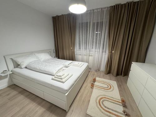 una piccola camera con un letto bianco e una finestra di Zen apartments a Craiova