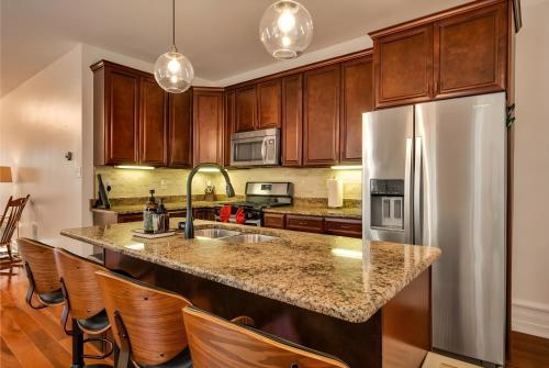 a kitchen with wooden cabinets and a stainless steel refrigerator at Downtown Lancaster Luxury 4BR - Garage & Parking in Lancaster