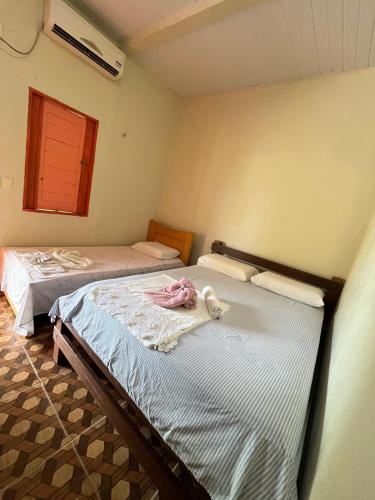 two twin beds in a room with a window at Pousada e Restaurante Cajutuba in Belterra