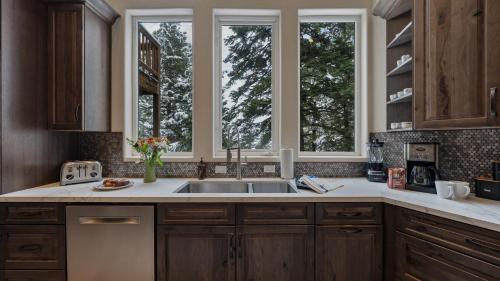a kitchen with a sink and two windows at Sparrow by AvantStay Modern Mountain Retreat w Hot Tub Pool Table Games in Truckee