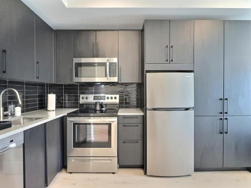 a kitchen with stainless steel appliances and gray cabinets at Modern Birmingham Retreat, Steps to Parks and Eats in Birmingham