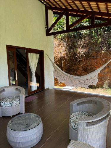 a room with two wicker chairs and a hammock at Casa Aconchego da Serra - Pacoti in Pacoti