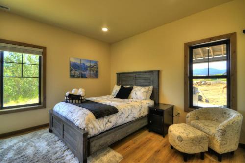 a bedroom with a bed and a chair and windows at Summit Sky Retreat Red Lodge in Red Lodge