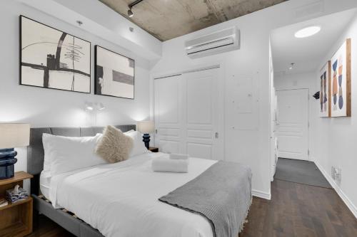 Un dormitorio blanco con una gran cama blanca y paredes blancas. en Flat at the Foot of the Mountain With Parking, en Montreal