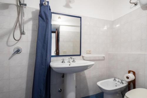 een badkamer met een wastafel, een toilet en een spiegel bij Appartamento Esperanza blu in Scauri