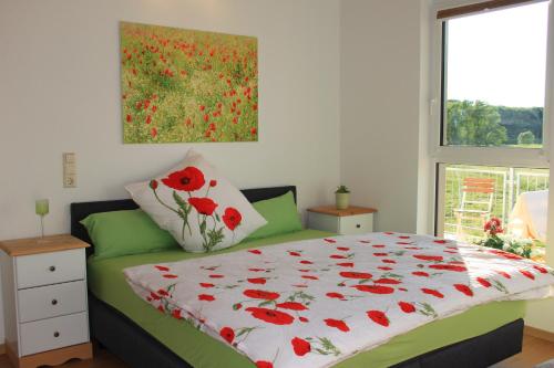 ein Schlafzimmer mit einem Bett mit einer roten Mohnblumen-Decke in der Unterkunft Fährhaus Gruna in Gruna
