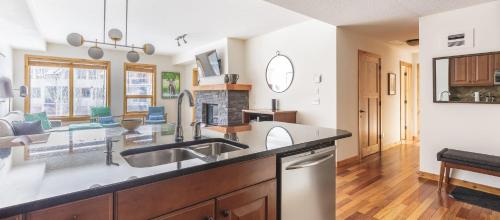 a kitchen with a sink and a living room at Tranquility at Rundle Cliffs Lodge in Canmore