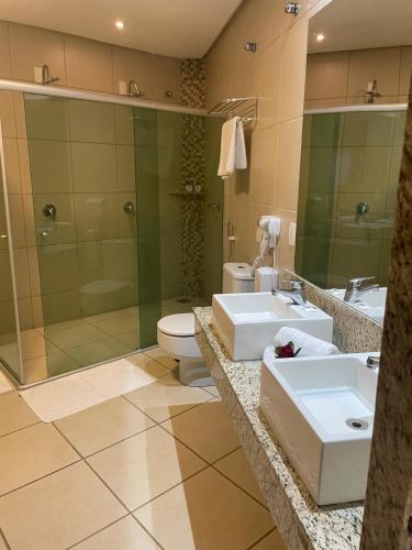 a bathroom with two sinks and a shower and a toilet at Hotel Canoeiros in Pirapora