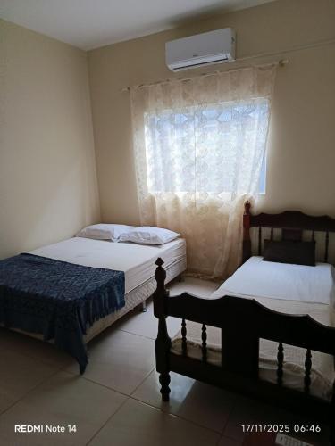 een slaapkamer met 2 bedden en een raam met een ventilator bij Josy House in Cabo Frio